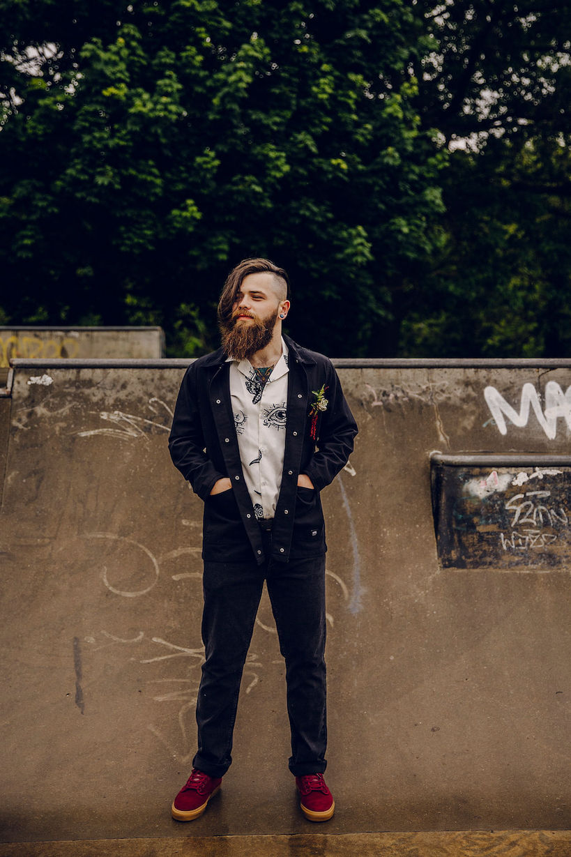 Emo groom with a mohawk wearing black jeans and jacket with patterned shirt and vanns.
