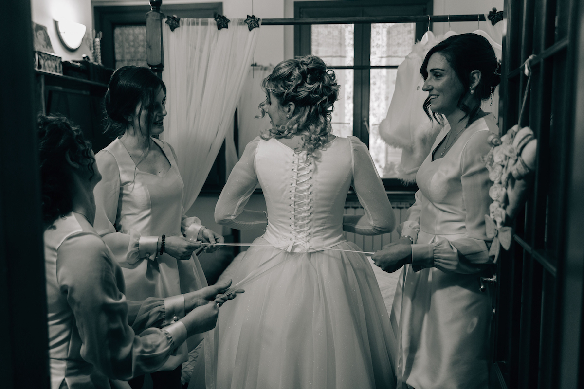 Bridesmaids tighten the corset on Brides handmade wedding dress