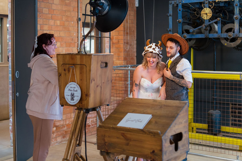 couple celebrating their wedding by dressing up in silly hats for the photobooth