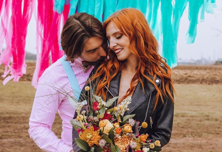 alternative bride wears leather bridal jacket and has long auburn hair.