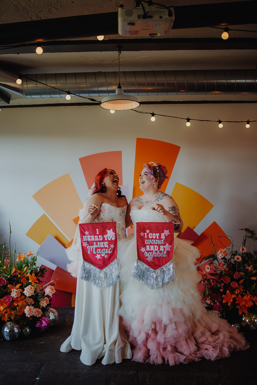 couple holding individual handmade fabric banners while standing in front of vibrant sunshine ceremony backdrop