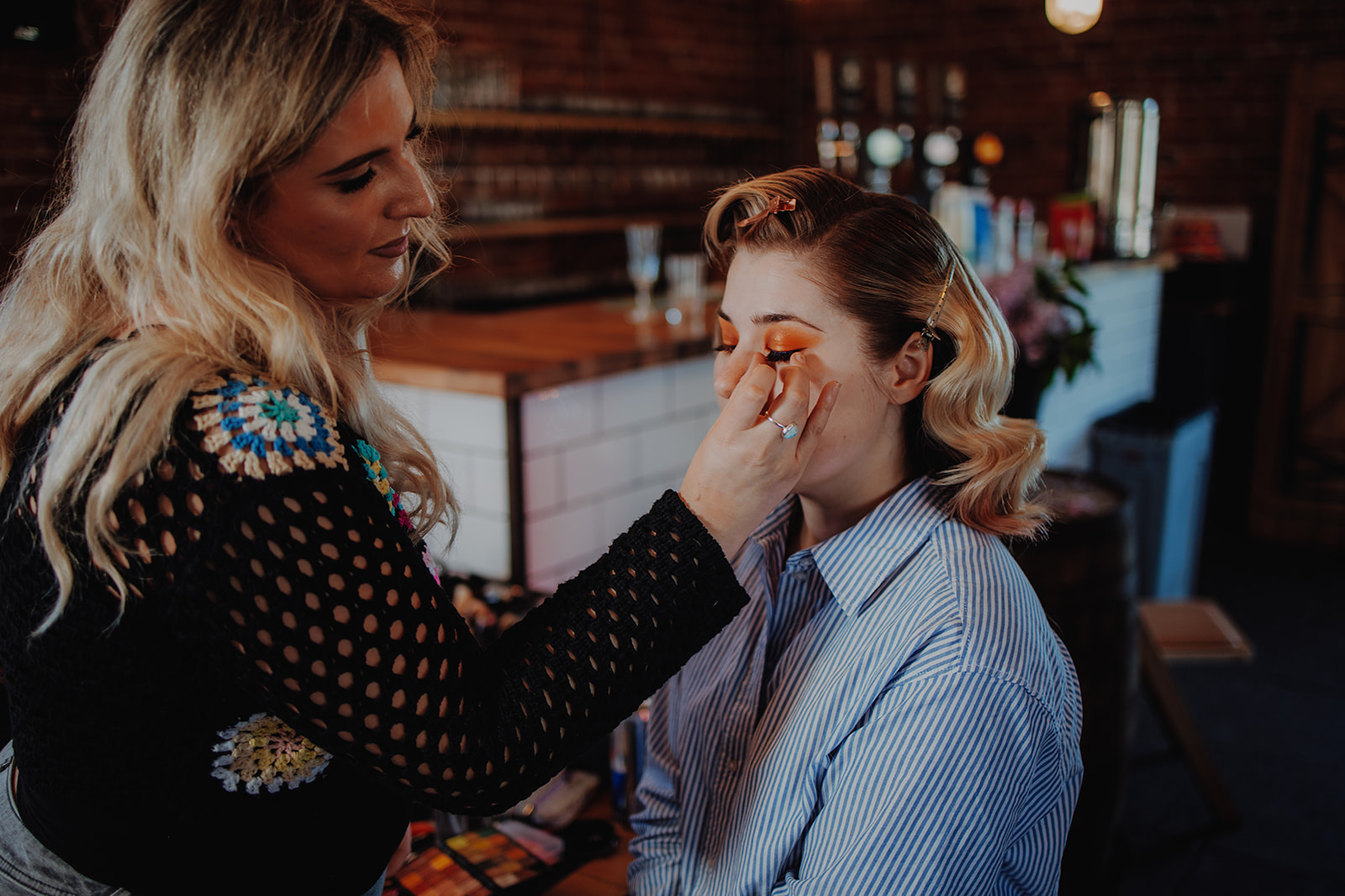 Alternative wedding make up artist applying bright orange eye shadow to the bride for individual wedding look