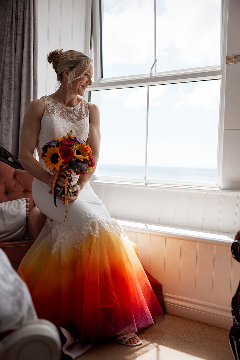 Bride wearing a bright alternative dip dye wedding dress holding coordinating bright wedding bouquet