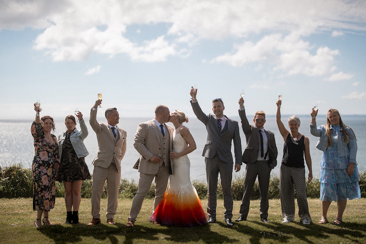 bride and groom kiss while their 7 guests toast them at their personal micro elopement wedding
