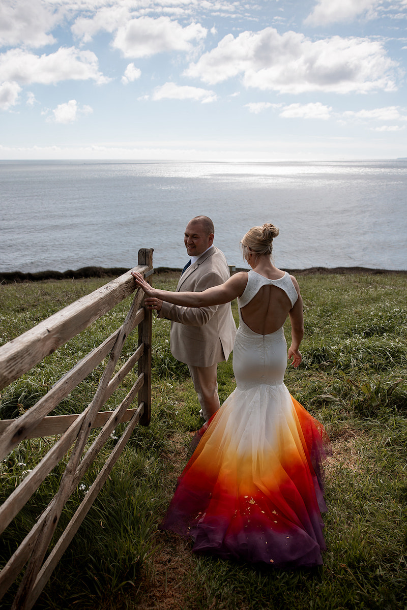 bride wearing a dip dye fish tail wedding dress with her groom walking the Cornish footpath on their personal micro elopement
