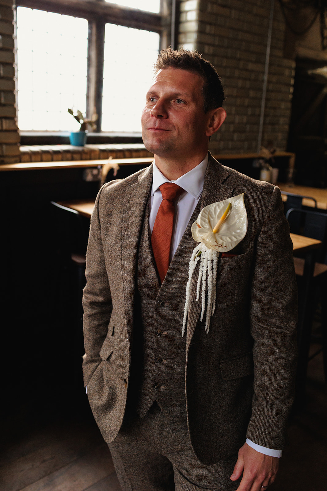 groom portrait - wearing brown tweed 3 piece suit with burnt orange tie and striking white buttonhole