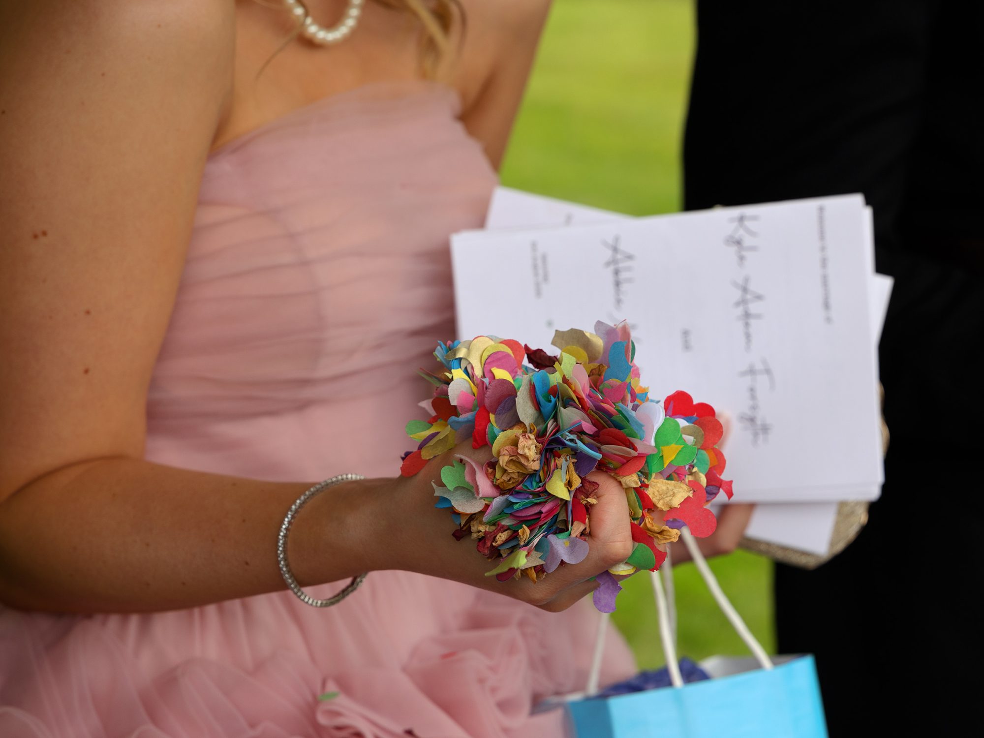 wedding guest holding a large handful of brightly coloured wedding confetti