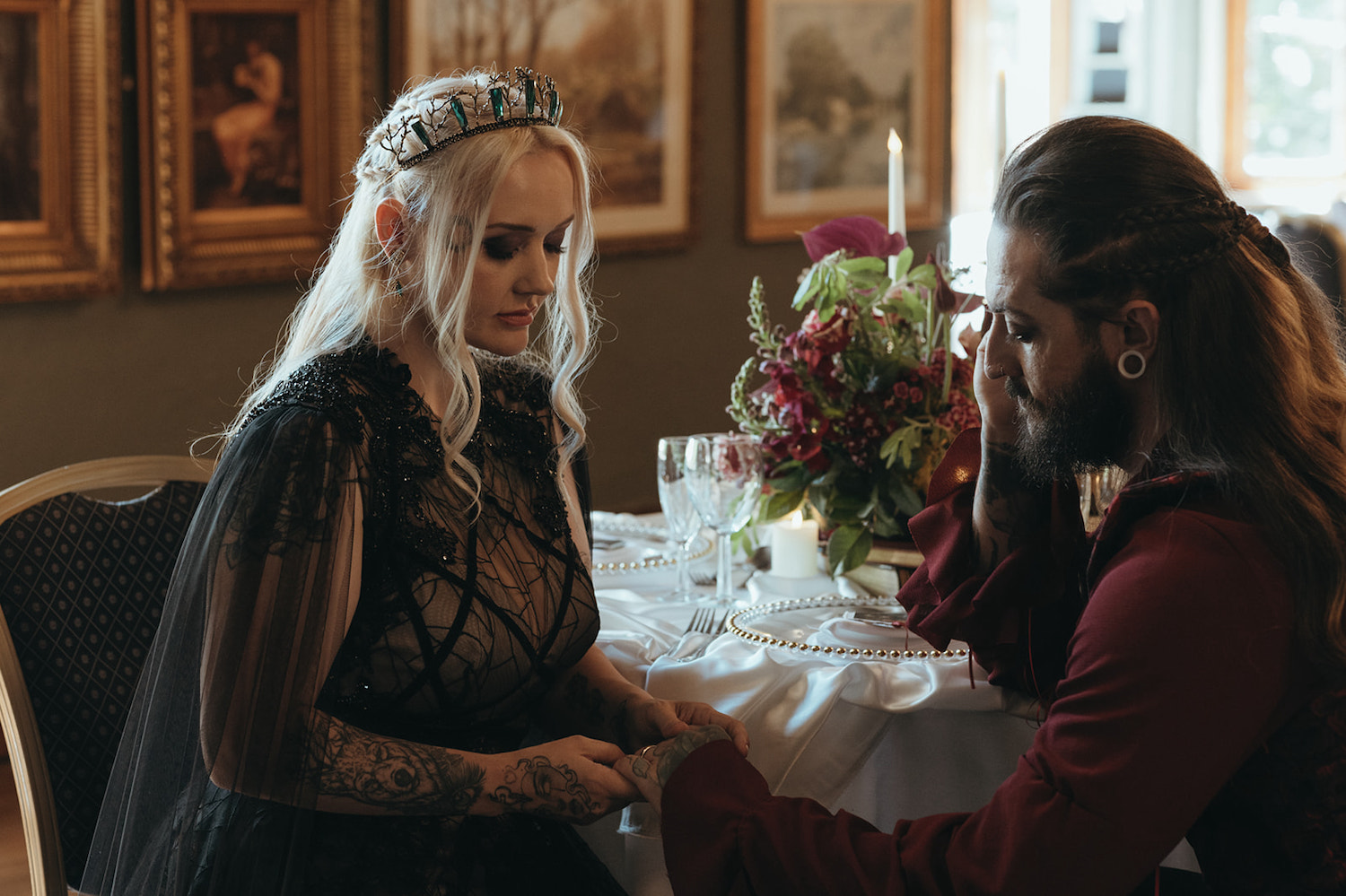 bride wearing black lace wedding dress and crown holding hands with her historic fantasy inspired dressed groom.