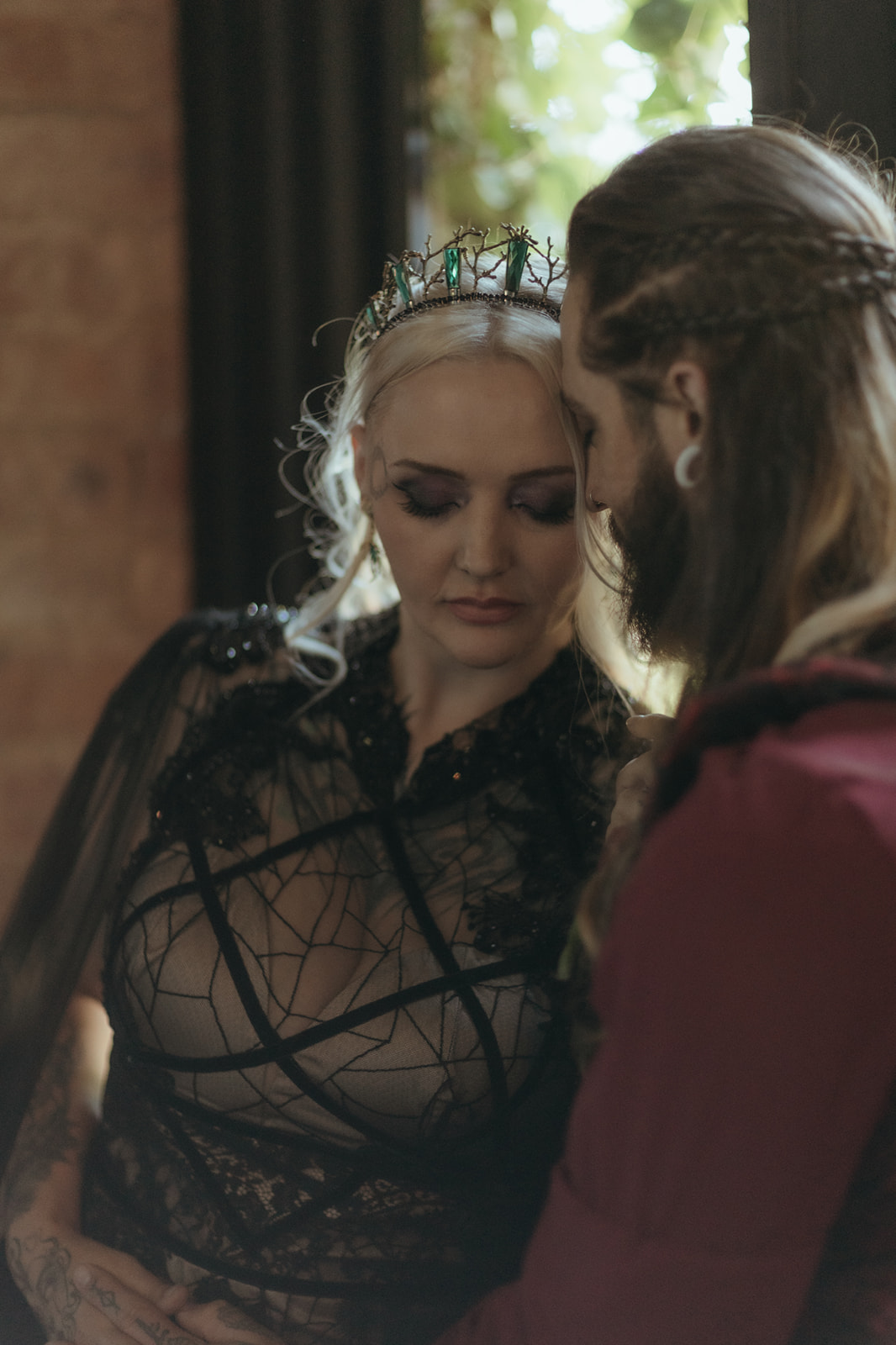 soft romantic image of a gothic bride wearing a branch crown leaning into her groom