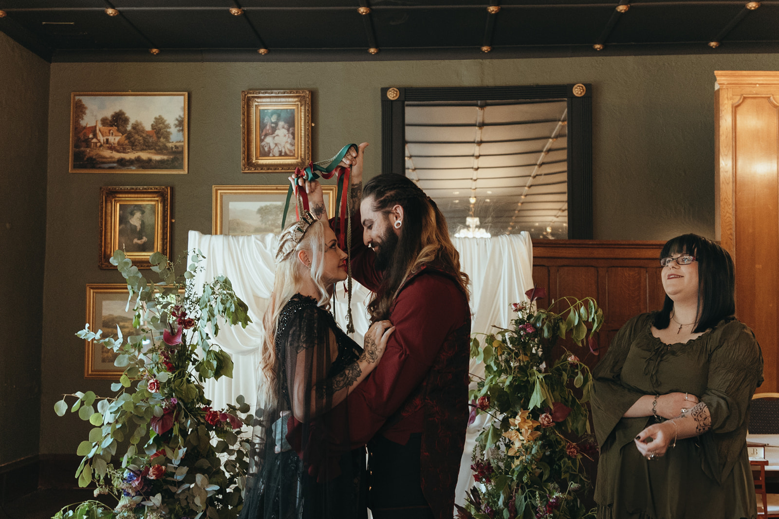 bride and groom hold handfasting ribbons above their heads as part of gothic wedding ceremony