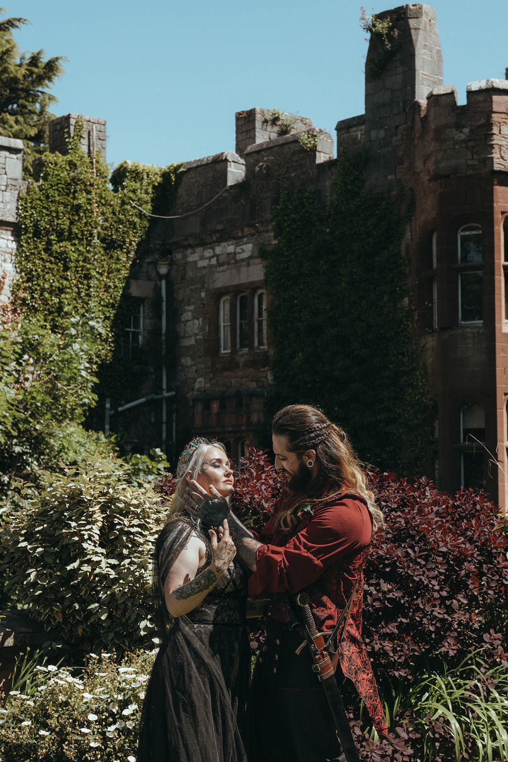 gothic bride and groom embrace outside of the castle wedding venue