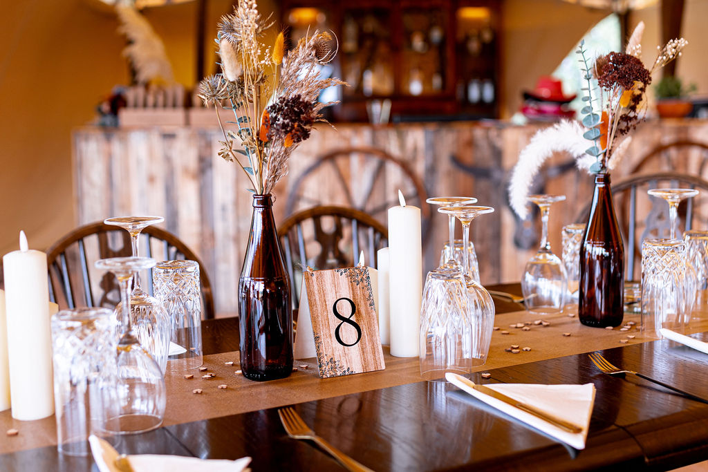 Rustic wedding breakfast table stying with glass bottles and dried flowers
