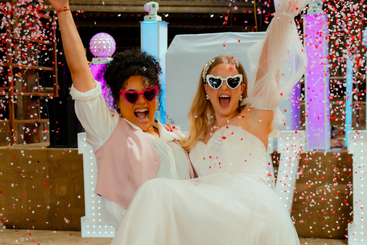 bride couple cheer while confetti falls down in part barn