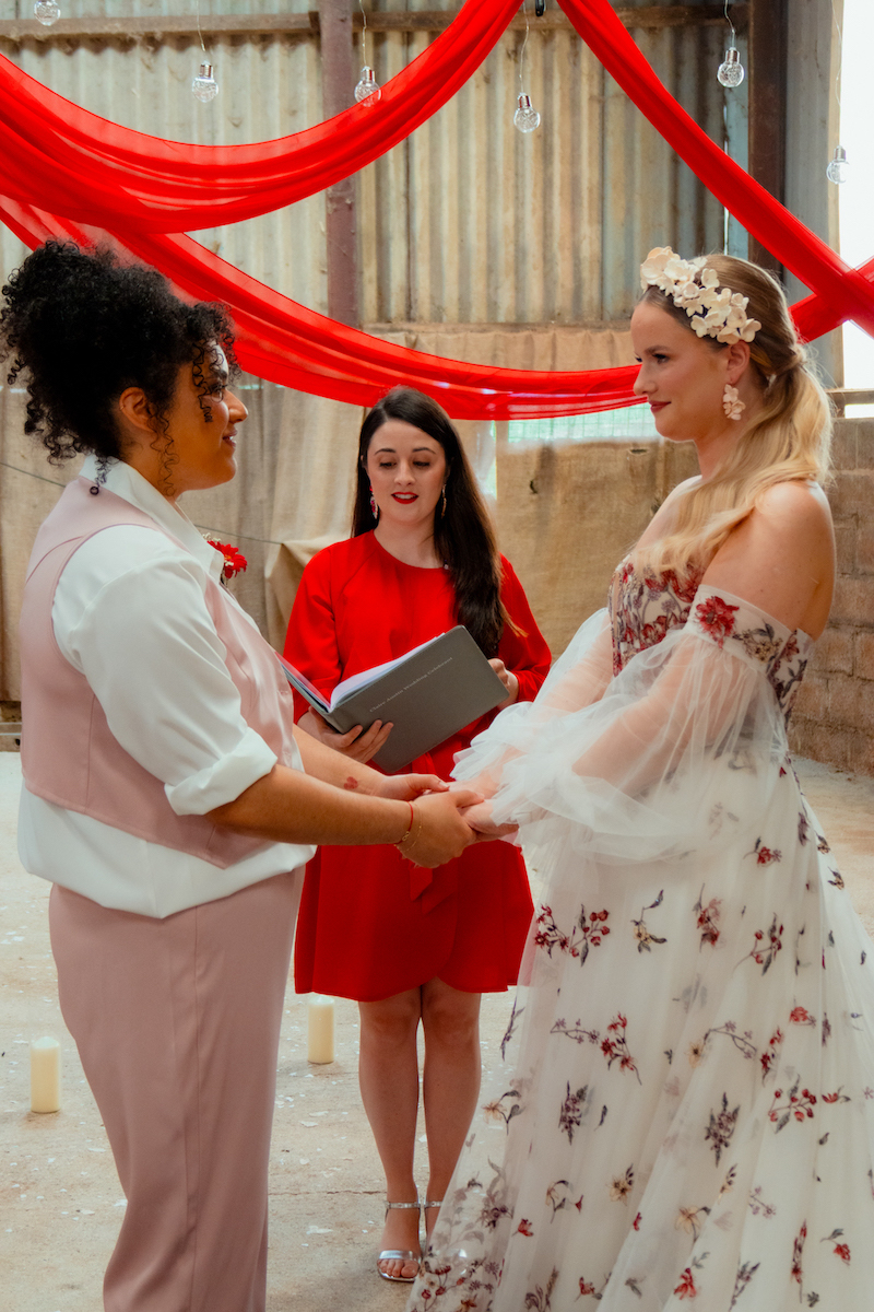 bride couple holding hands in front of wedding celebrant as part of wedding ceremony