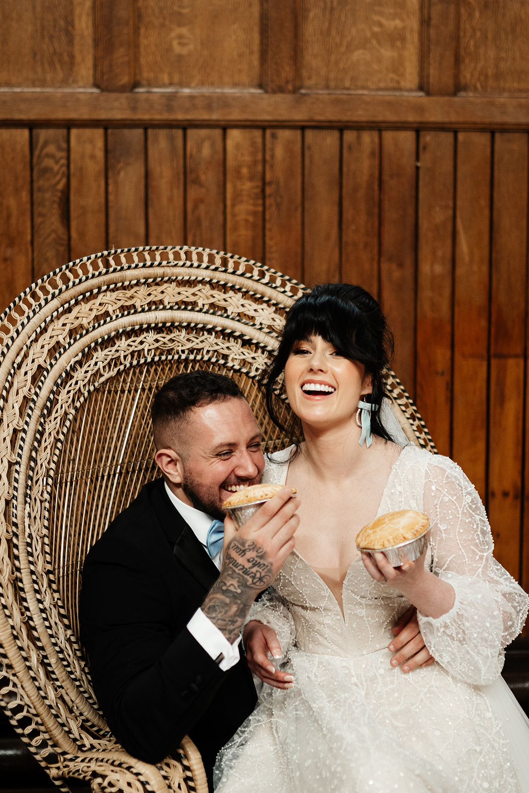 bride and groom sat on peacock chair eating pies and part of northern wedding breakfast