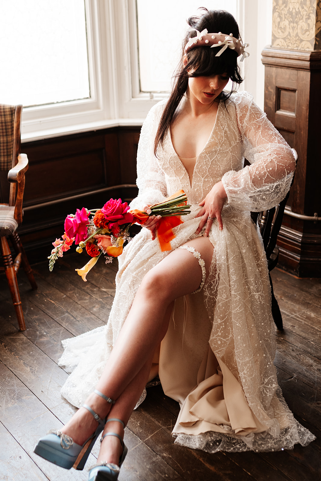 bride sat wearing lace wedding dress showing her handmade lace flower garter