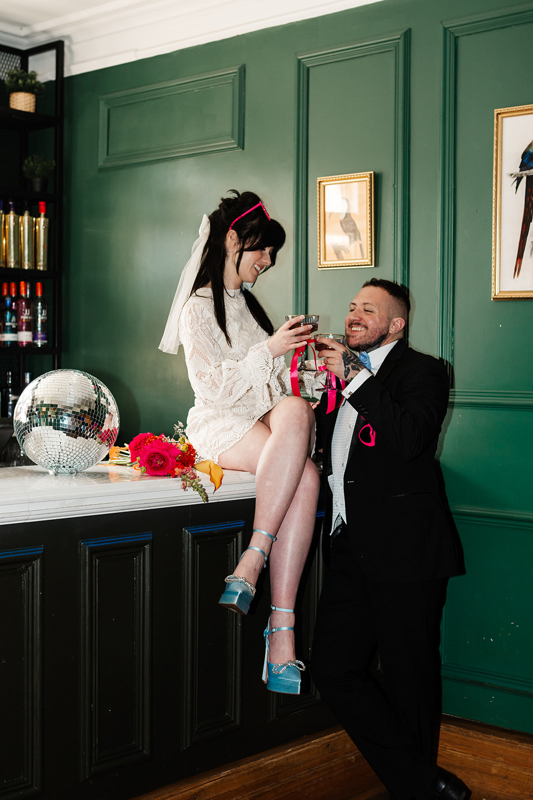 retro bride with beehive sits on a bar wearing short wedding dress