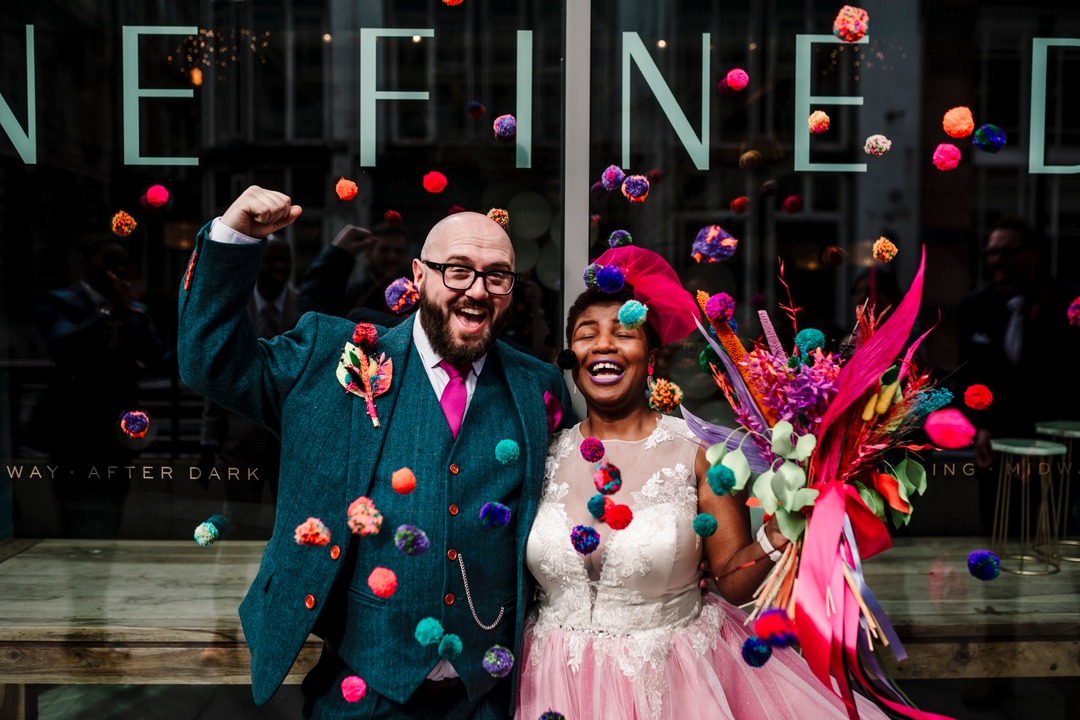 alternative bride and groom celebrate after getting married, bride wears a pink coloured wedding dress.