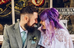 alternative bride and groom share an intimate moment. bride has purple hair and ethereal style wedding dress