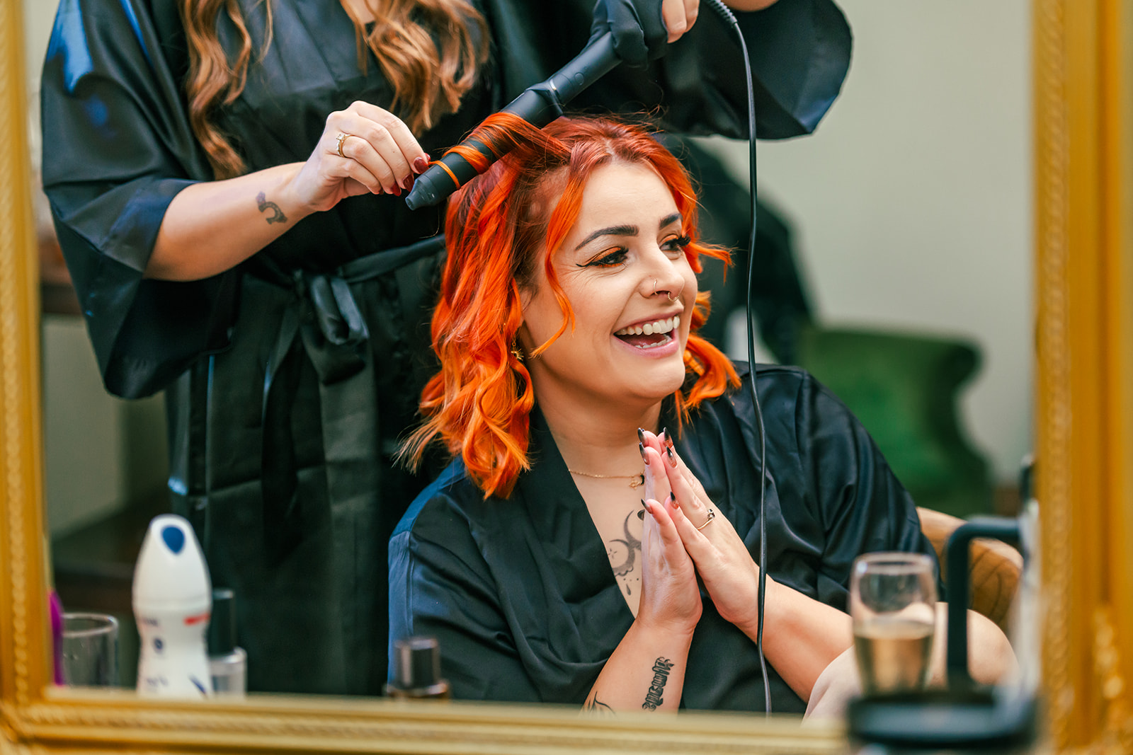 portrait of the bridesmaid curling the bride's bright orange hair for the wedding day.