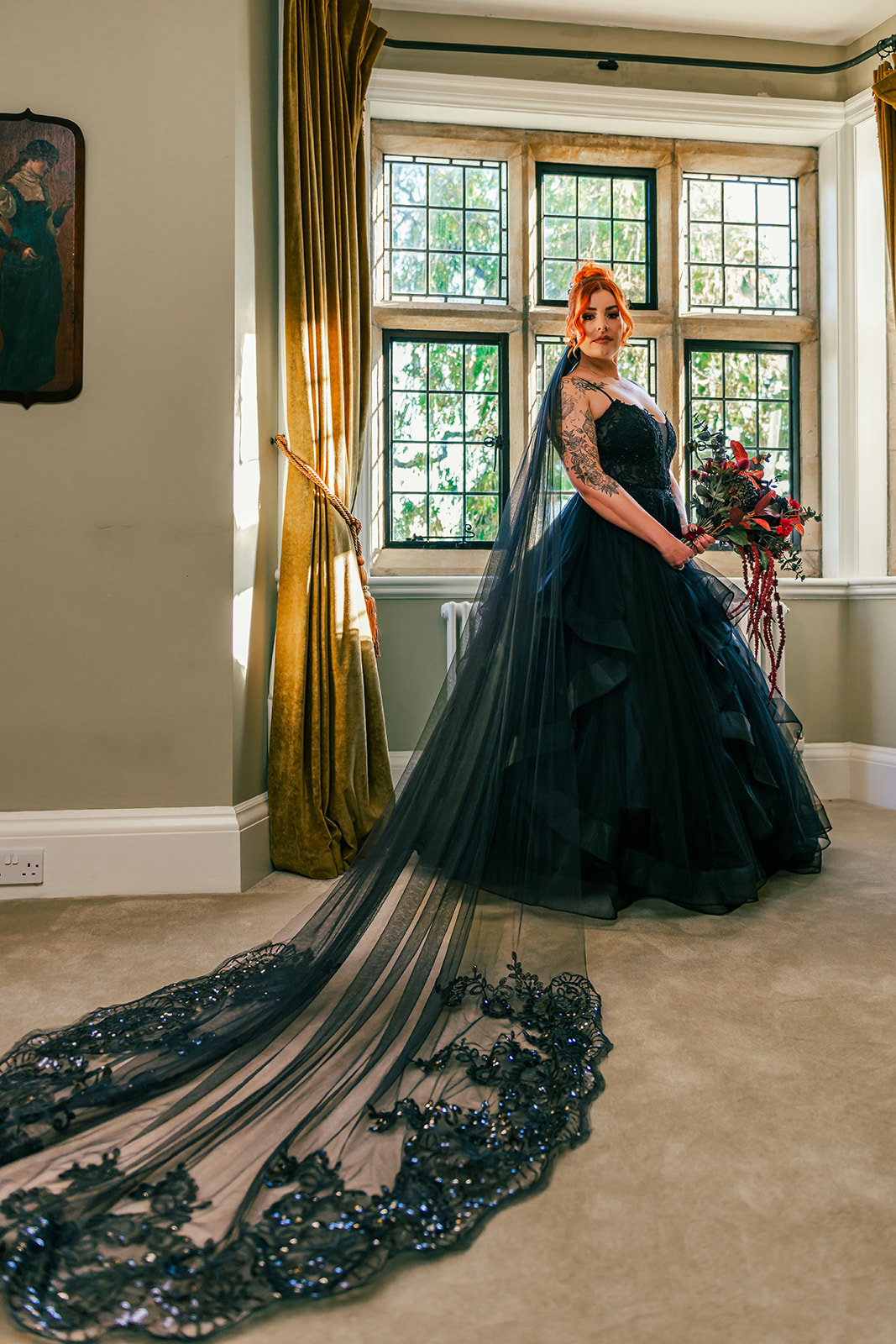 Bridal portrait showing a bride wearing a multi layered black tule wedding dress and statement long beaded black veil