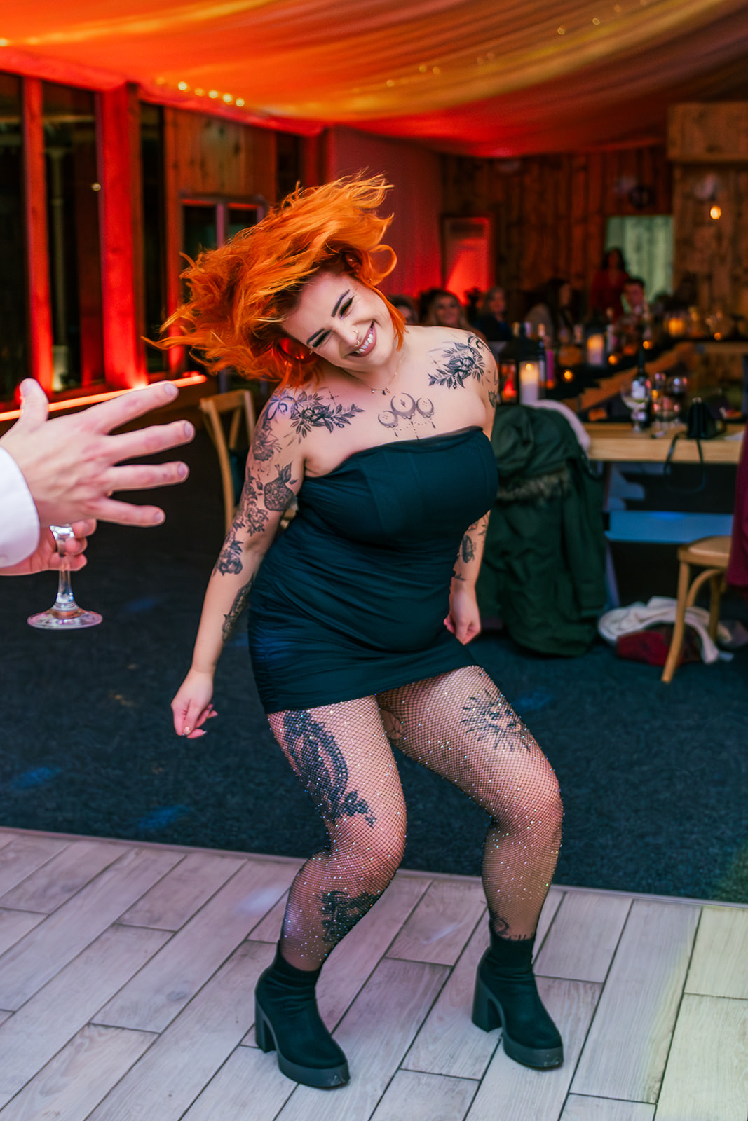 Bride in short black mini dress and glittery fishnet tights dances - shaking her pumpkin orange hair