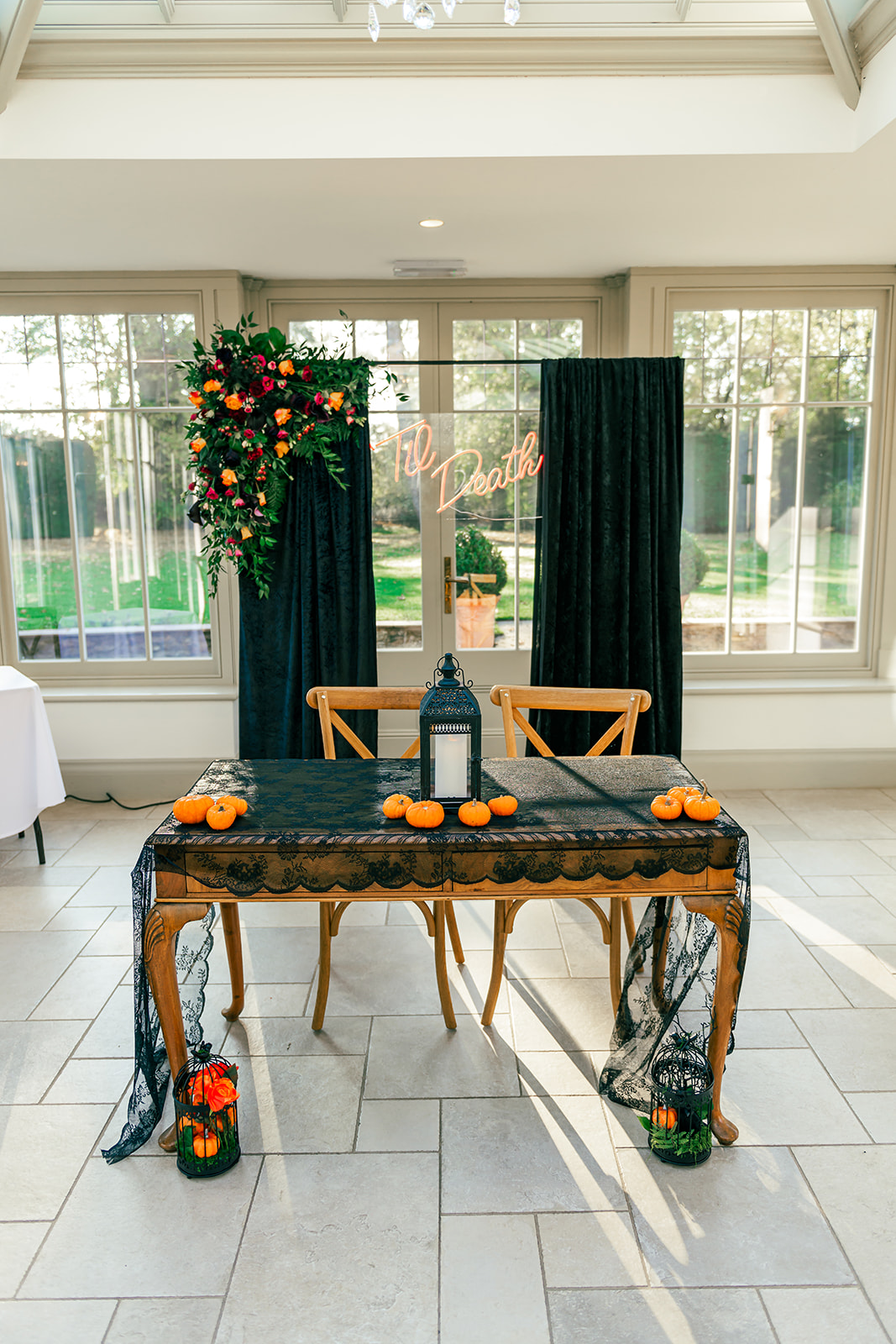 detail shot of the wedding ceremony area including black drapes, pumpkins, black lanterns and orage, red and purple florals