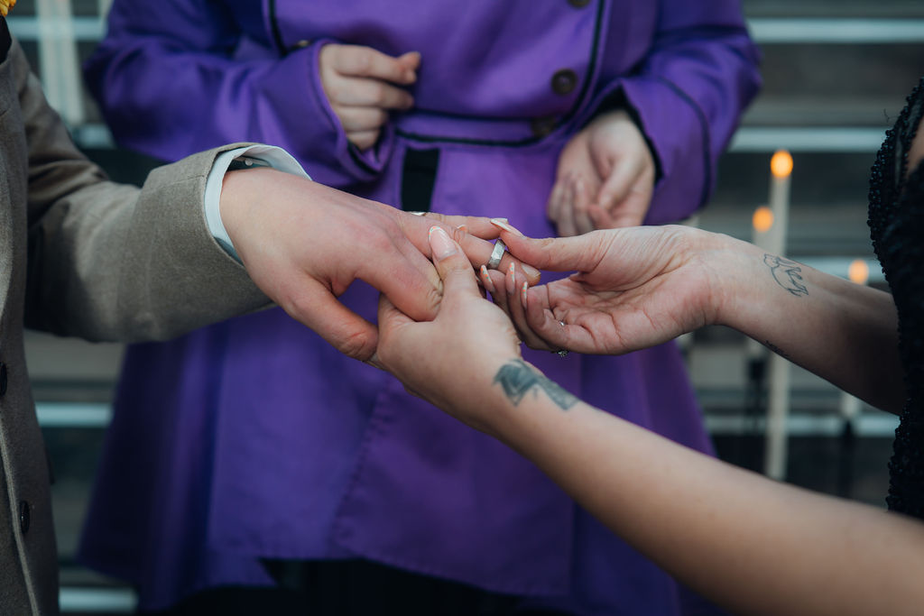 detail shot of the bride placing a handmade wedding ring onto the grooms finger