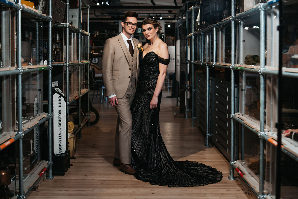 newly weds post together for couple portrait between shelves of artefacts at an alternative museum wedding venue
