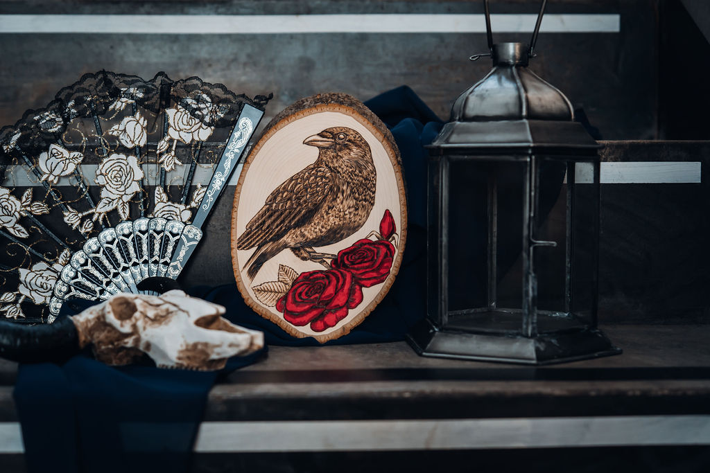 Pyrography raven sat on roses with skull and lantern as part of the wedding ceremony decor