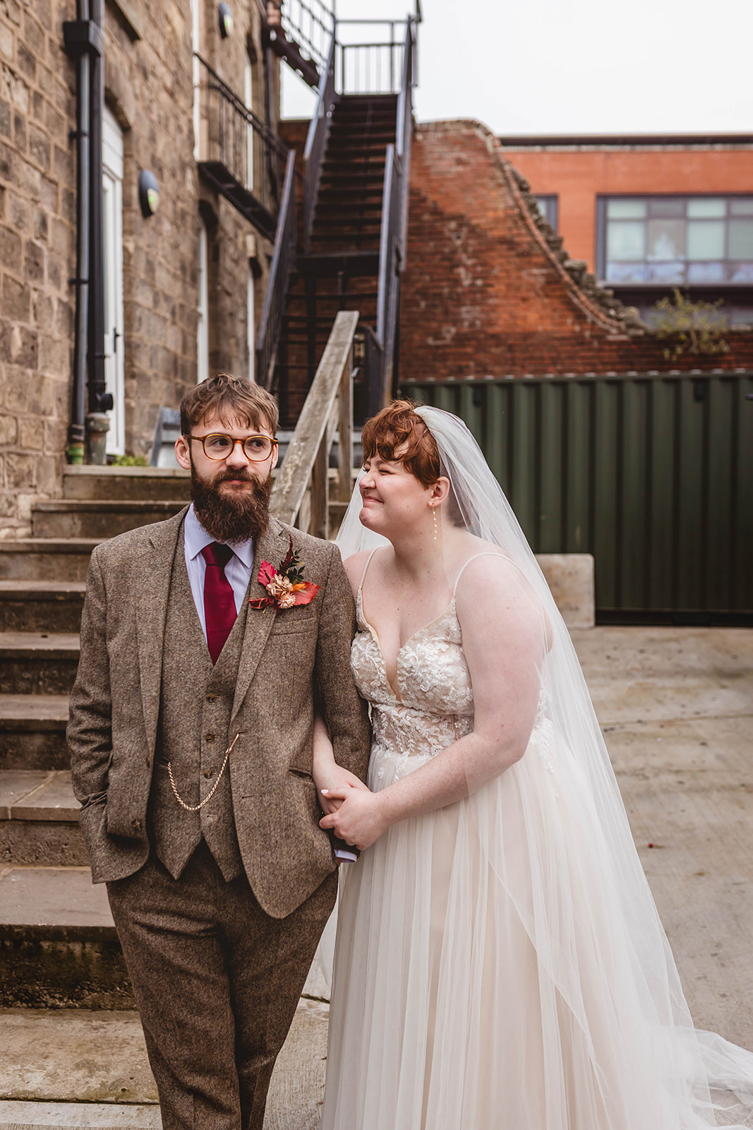 bride with short hair holding husbands arm as part of couple portrait for autumn wedding