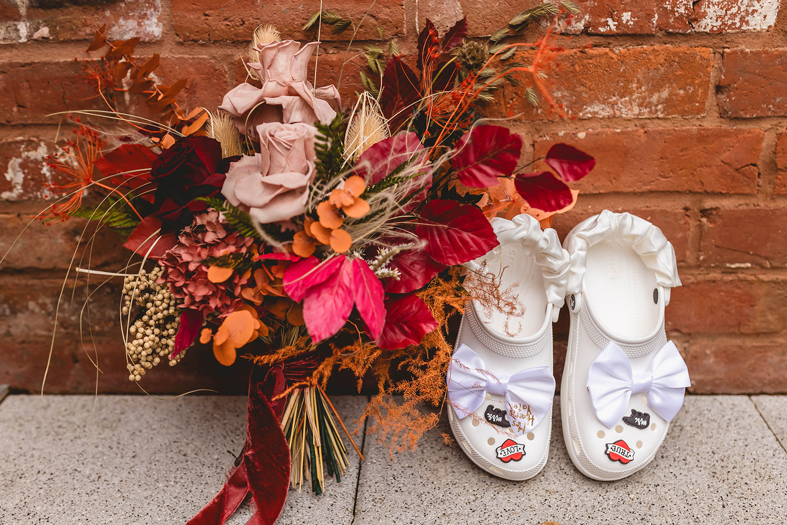 detail shot of the brides wedding bouquet featuring autumnal colours next to her wedding day crocs