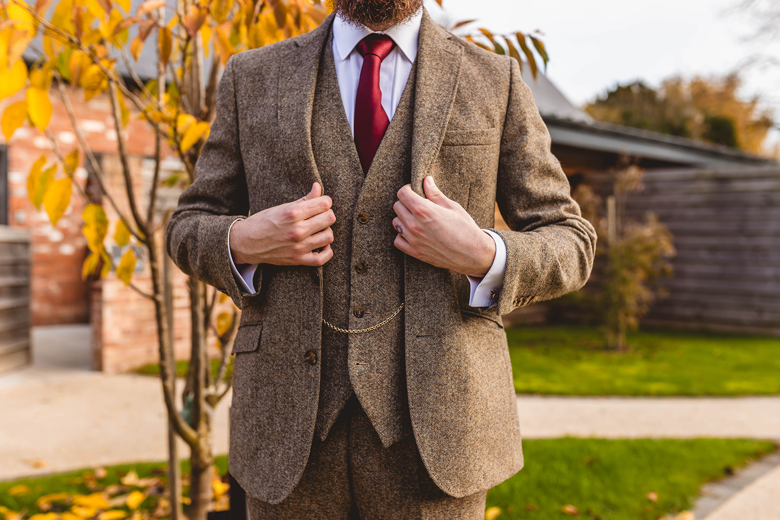 detail shot showing the groom's brown 3 piece tweed suit and burgundy tie