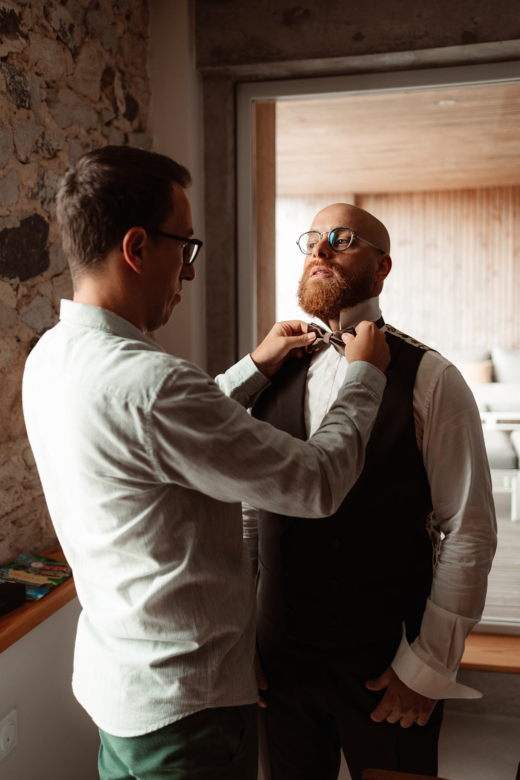 groom having his bow tie fixed by a friend