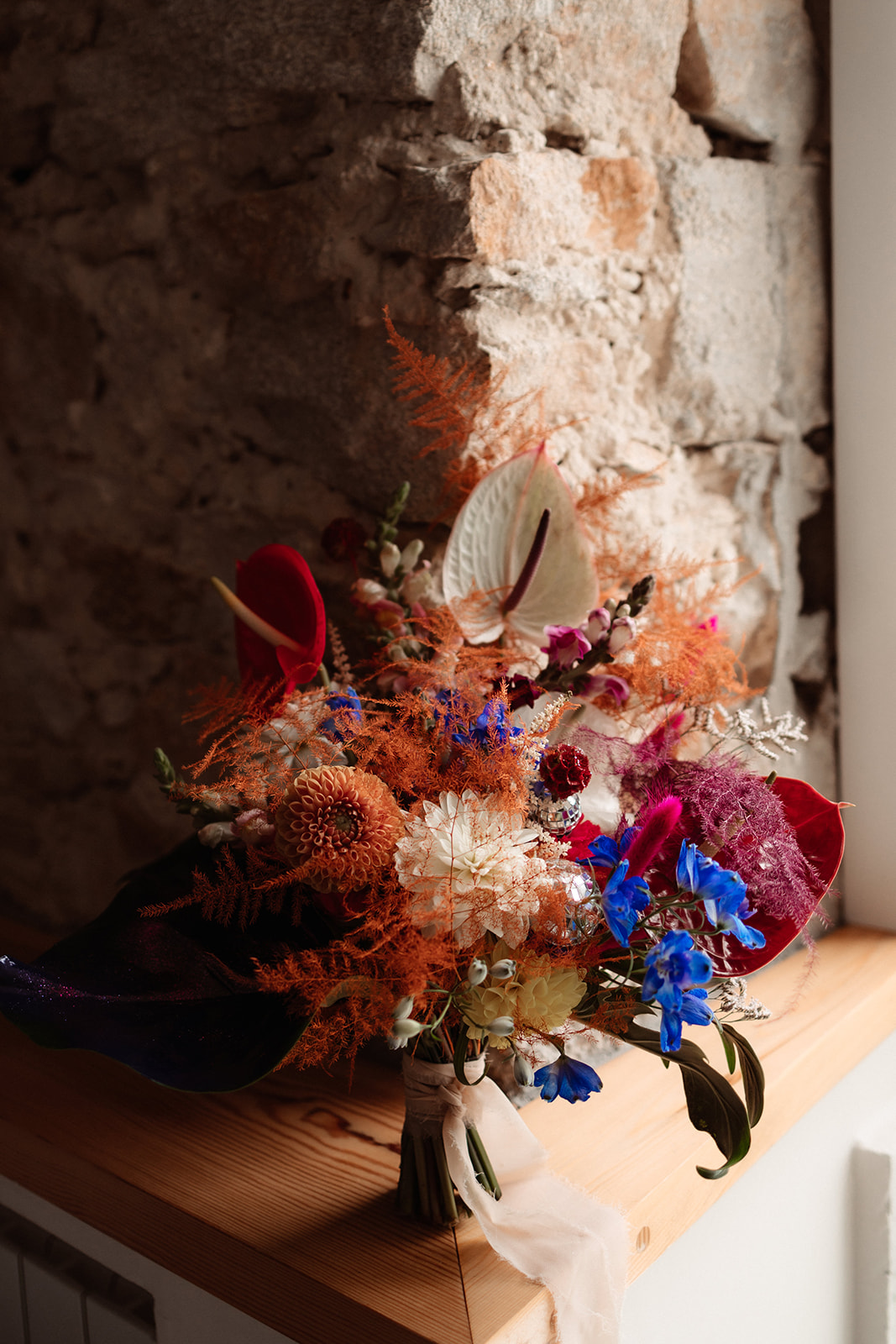 detail shot of bridal bouquet made from red, blue, orange and white florals