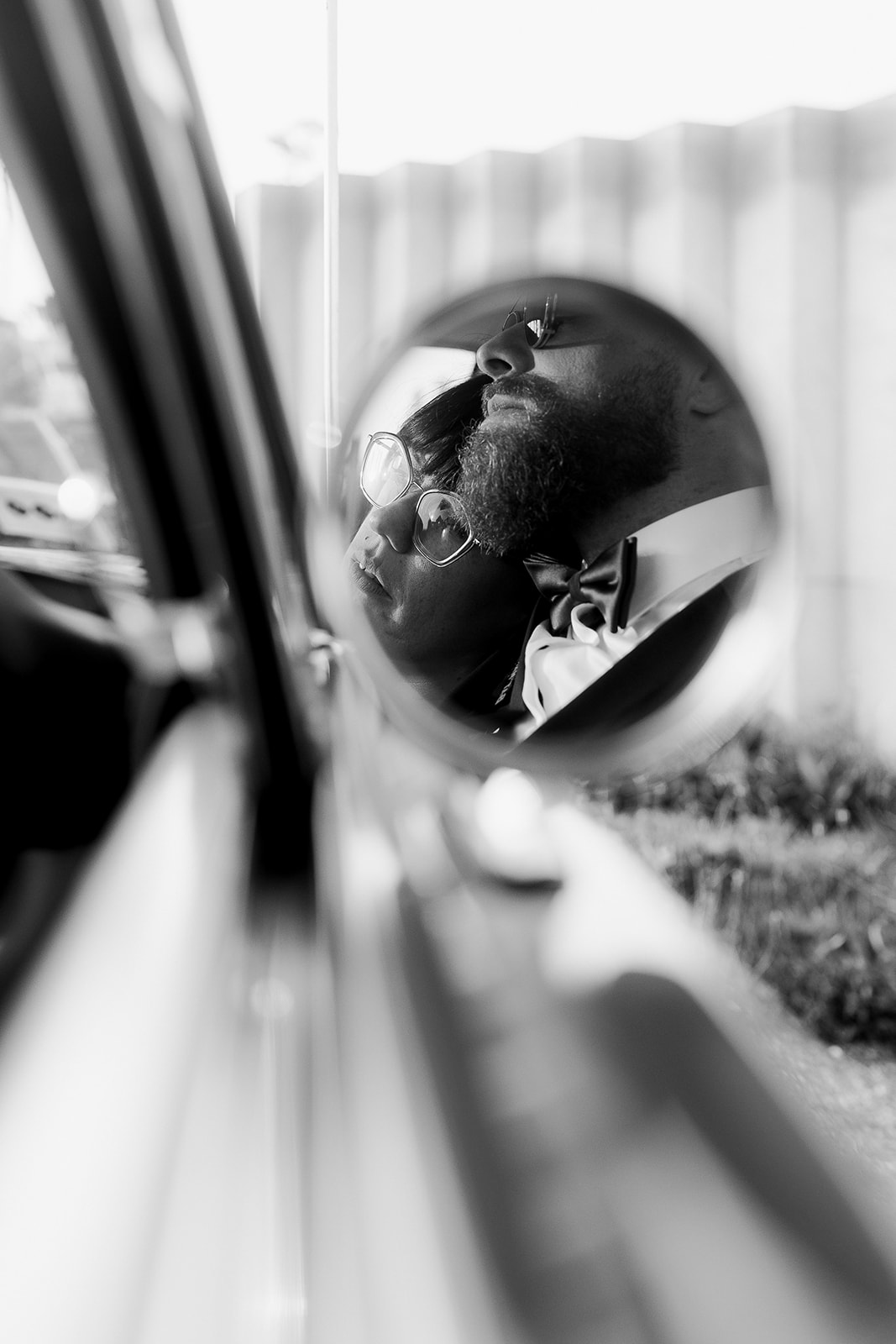 Arty couple portrait where the couple are only visible in a car side mirror - everything else is faided