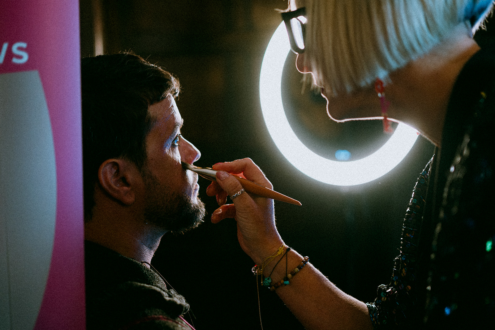 Detail shot of makeup artist Zoe Fidgeon applying makeup to the groom