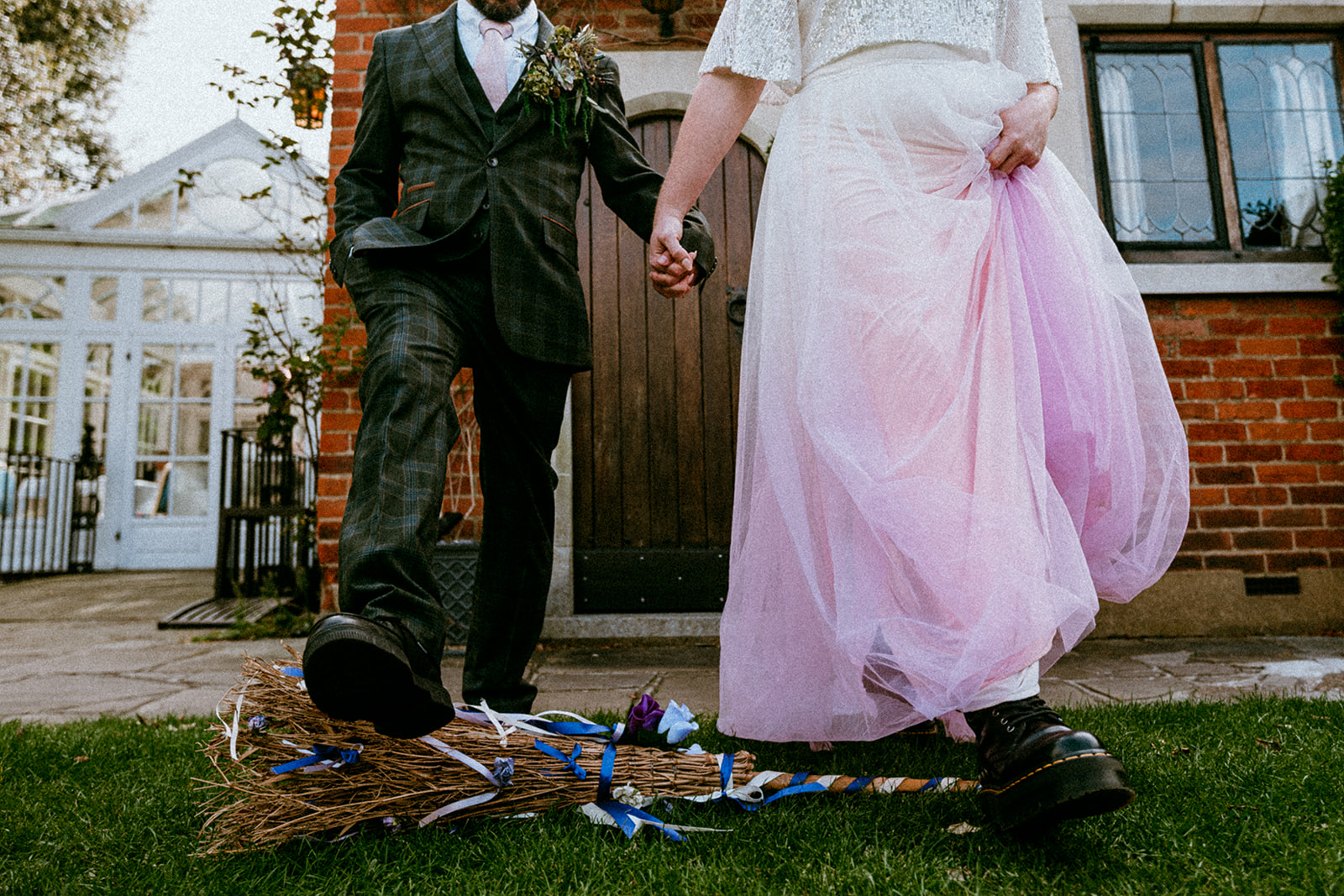 Couple jump the broom as part of a Wicked inspired wedding