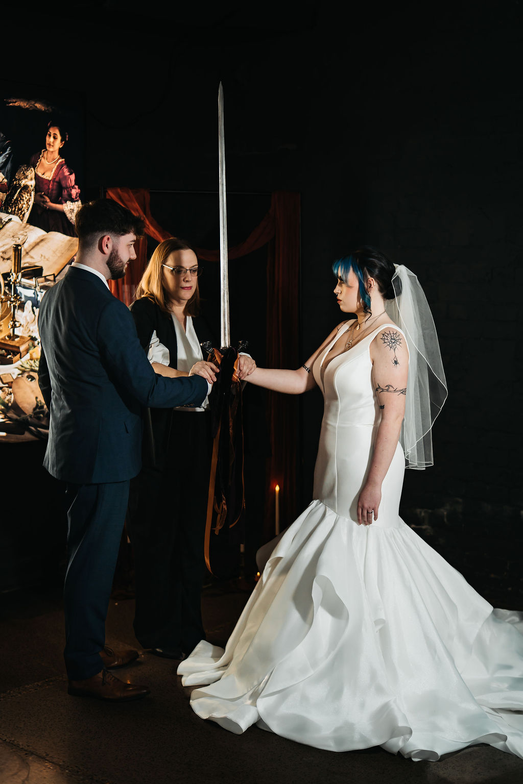 Photo of the wedding celebrant performing the viking sword ceremony - where the couple have their hands bound together with ribbons around the sword