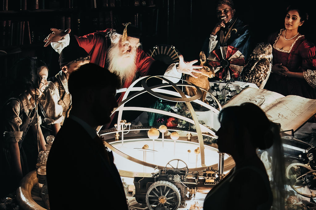 an illuminated Joseph Wright painting with a silhouette of the bride and groom in front as part of an industrial museum wedding.