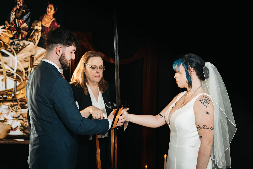 Couple have their hands bound with ribbons around a sword as part of a viking sword ceremony