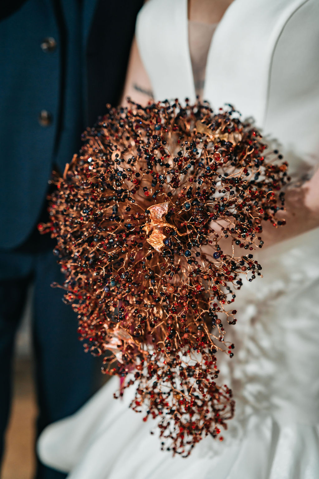 detail shot of the brides alternative wedding bouquet handmade with wire and beads and tiny copper dragons