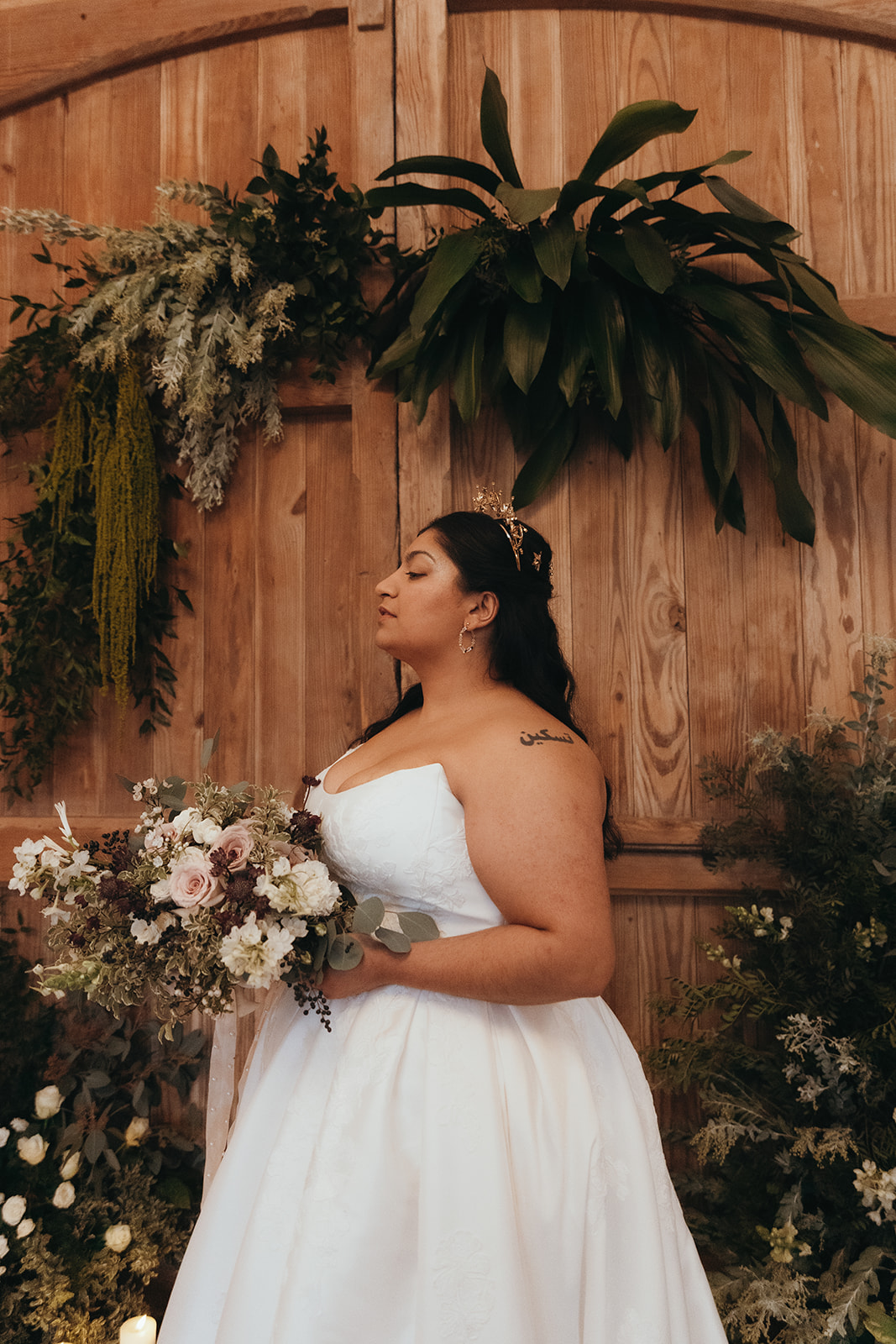 bride holding organic textured wedding bouquet stands in front of an asymmetric floral arch for Renaissance wedding