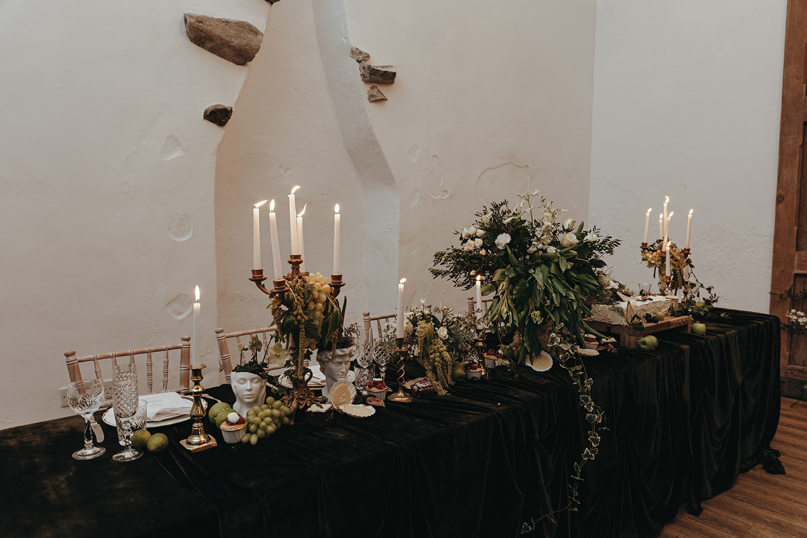 detail shot of the wedding breakfast table which has been inspired by renaissance art. It has stone urns and busts holding flowers and fruit