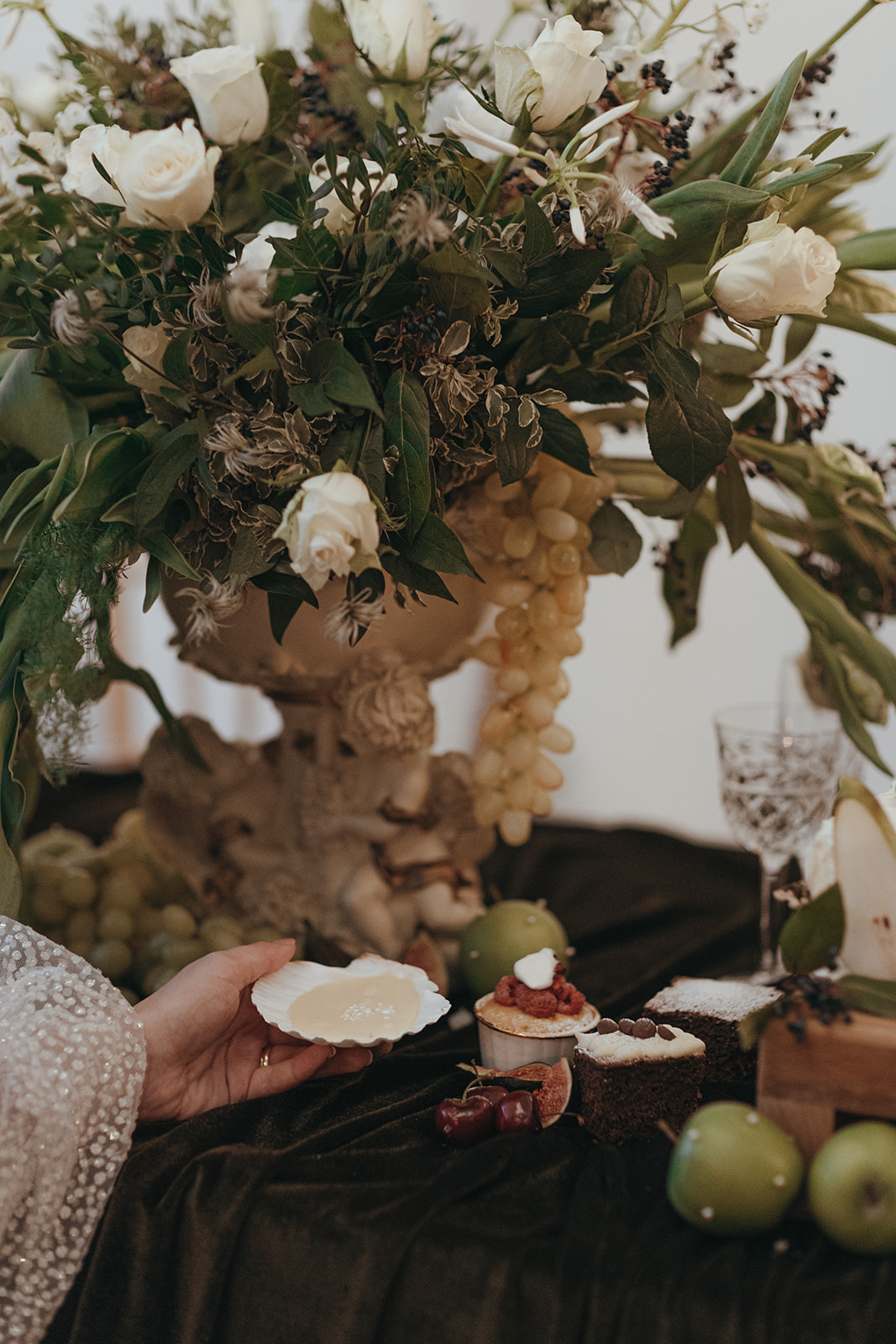 detail shot of a desert in a scollop shell with a white floral display in a ceramic stand