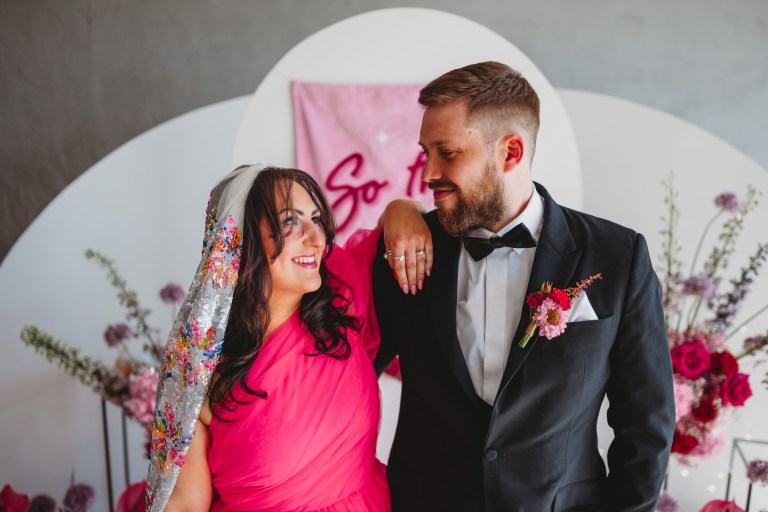 bride wears a pink wedding dress and groom wears a matching pink buttonhole.