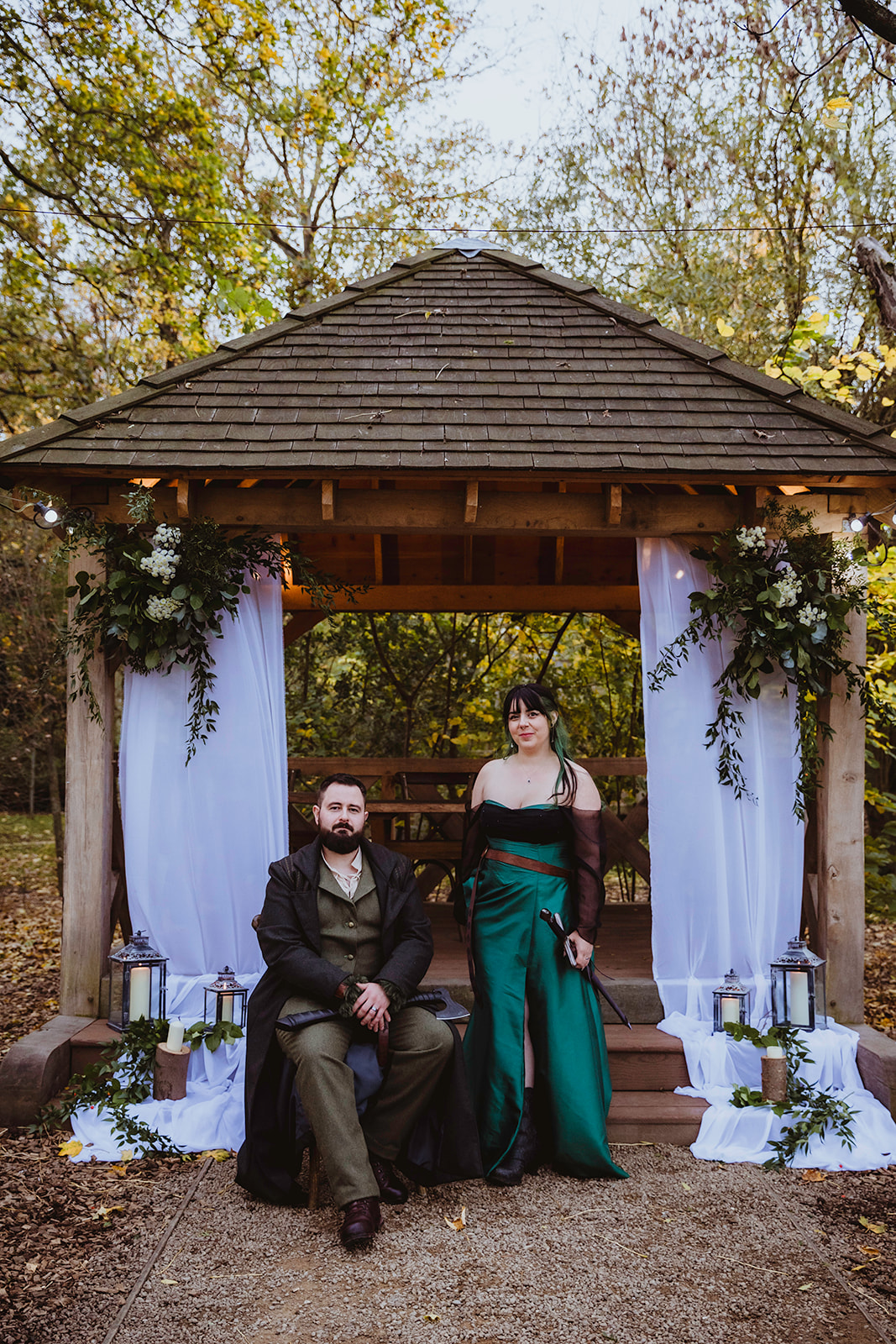 bride and groom positioned in front of their outdoor ceremony area with flowers, lanterns and candles