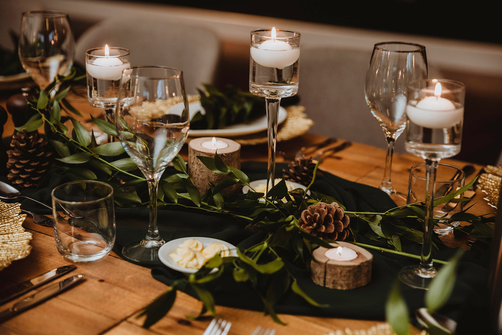 detail shot of the wedding breakfast banquet table which has candles, greenery and pine cones on it to decorate