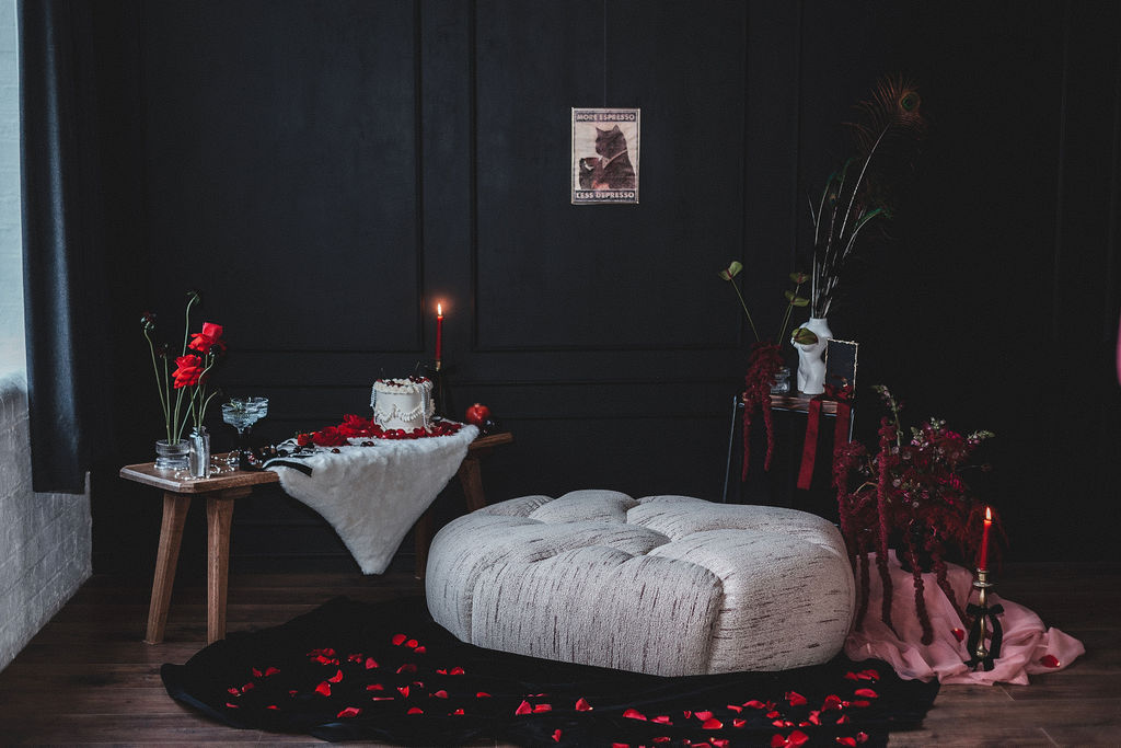 detail shot of the intimate dark romance setting with floor cushion low table, dark florals and wedding cake