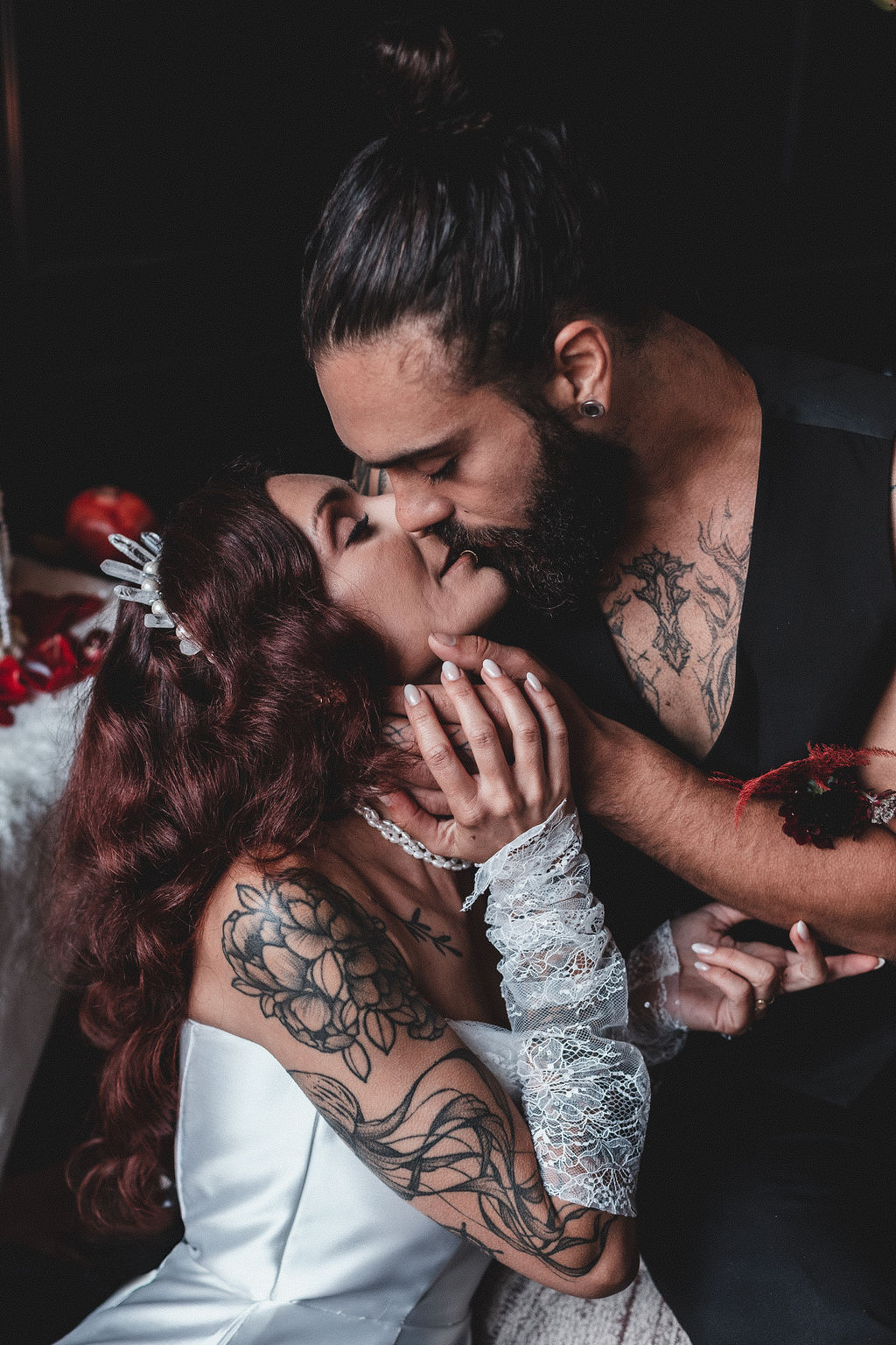 tattooed groom holding his brides face as he kisses her